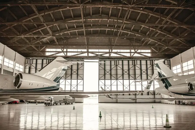 Aircraft parked inside a daylit hangar above a bright, seamless coated floor