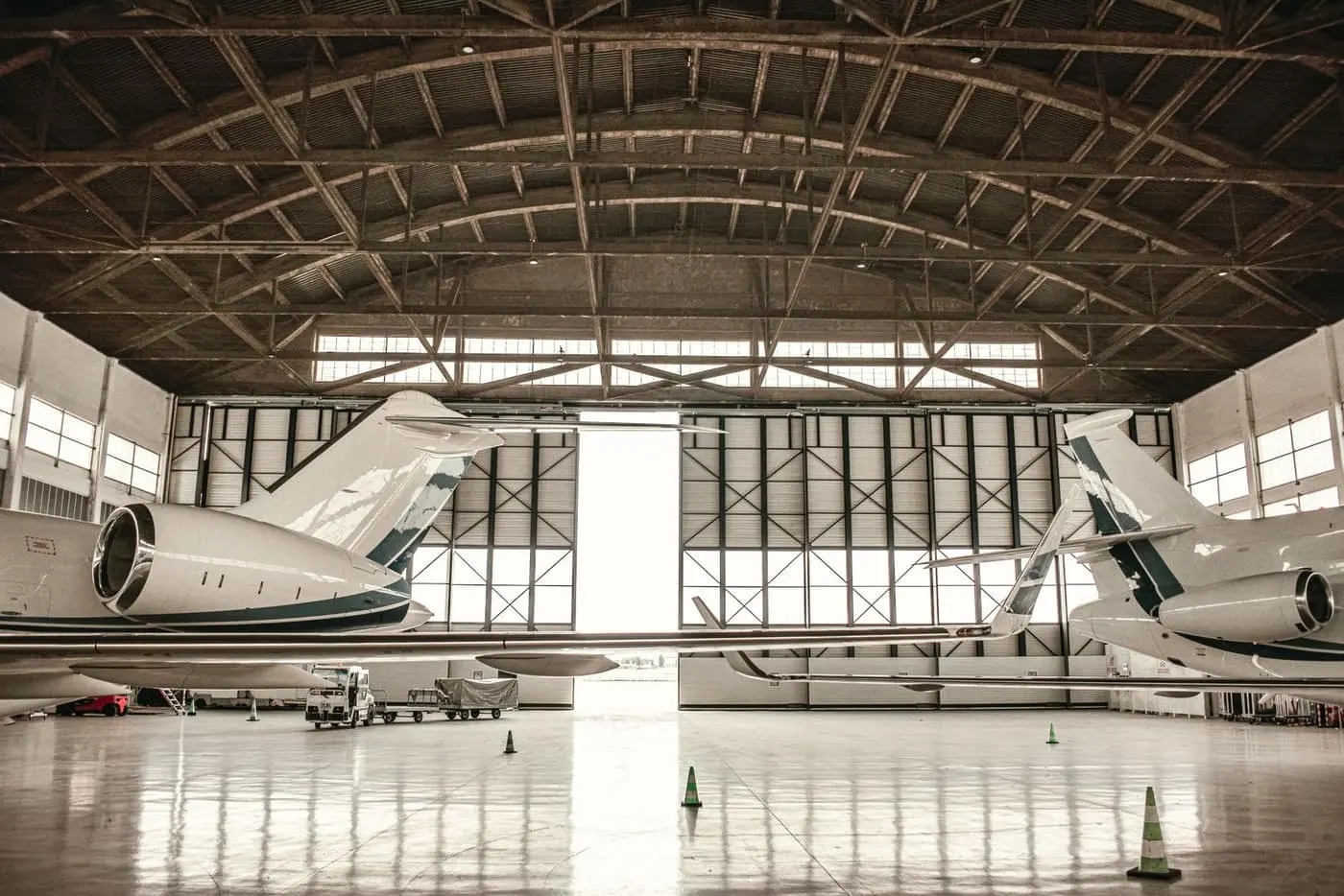 Aircraft parked inside a daylit hangar above a bright, seamless coated floor