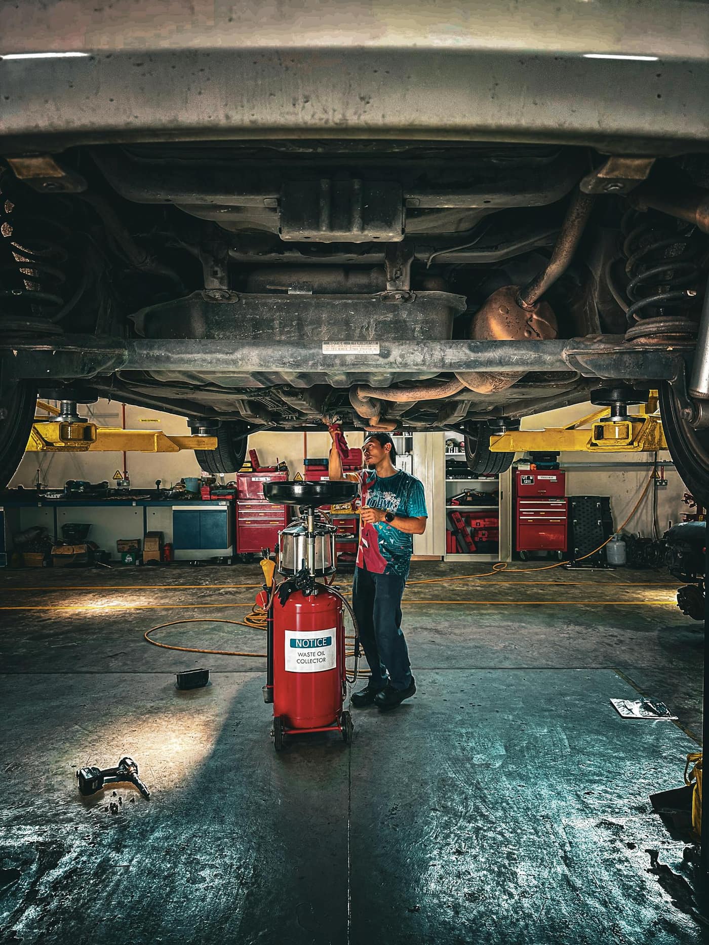 Technician working under a vehicle in a service bay