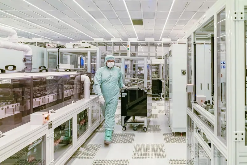 Gowned technician in a classified cleanroom standing on a seamless, low-particulate resinous floor