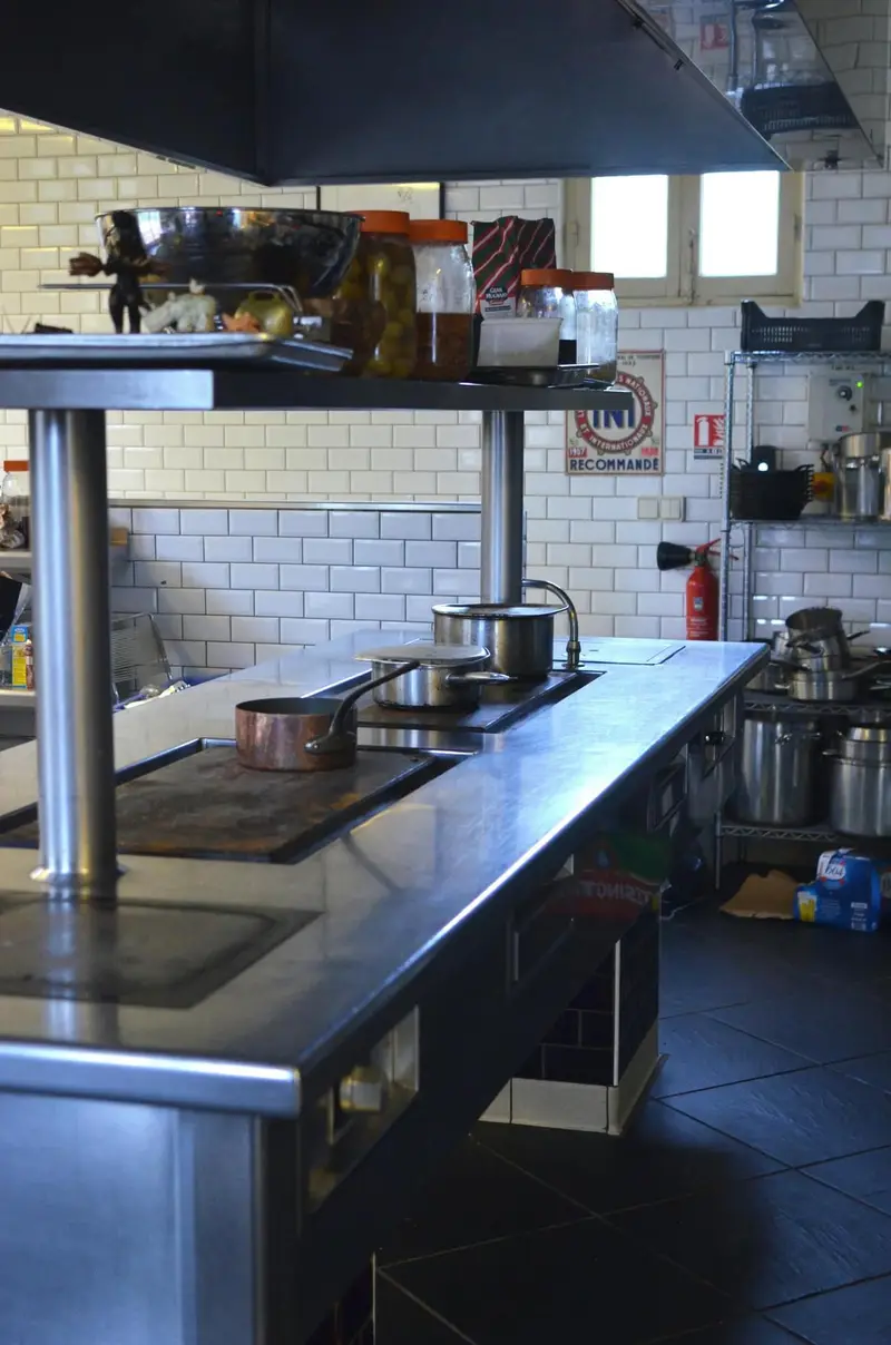 Stainless steel cookline and prep stations in a working commercial kitchen above a seamless floor
