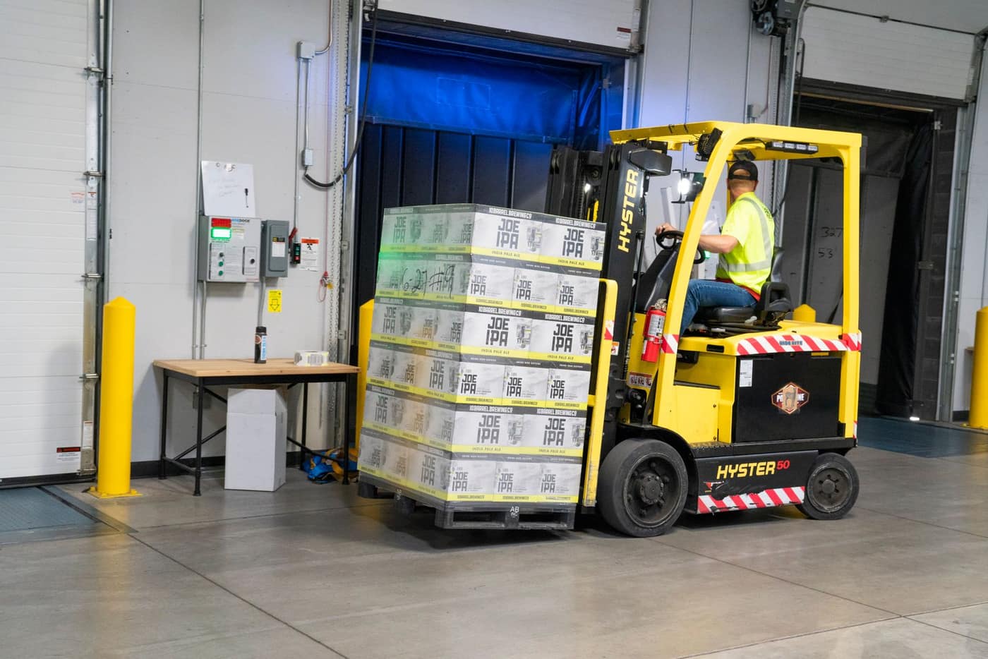 Counterbalance forklift carrying a loaded pallet across a concrete dock floor