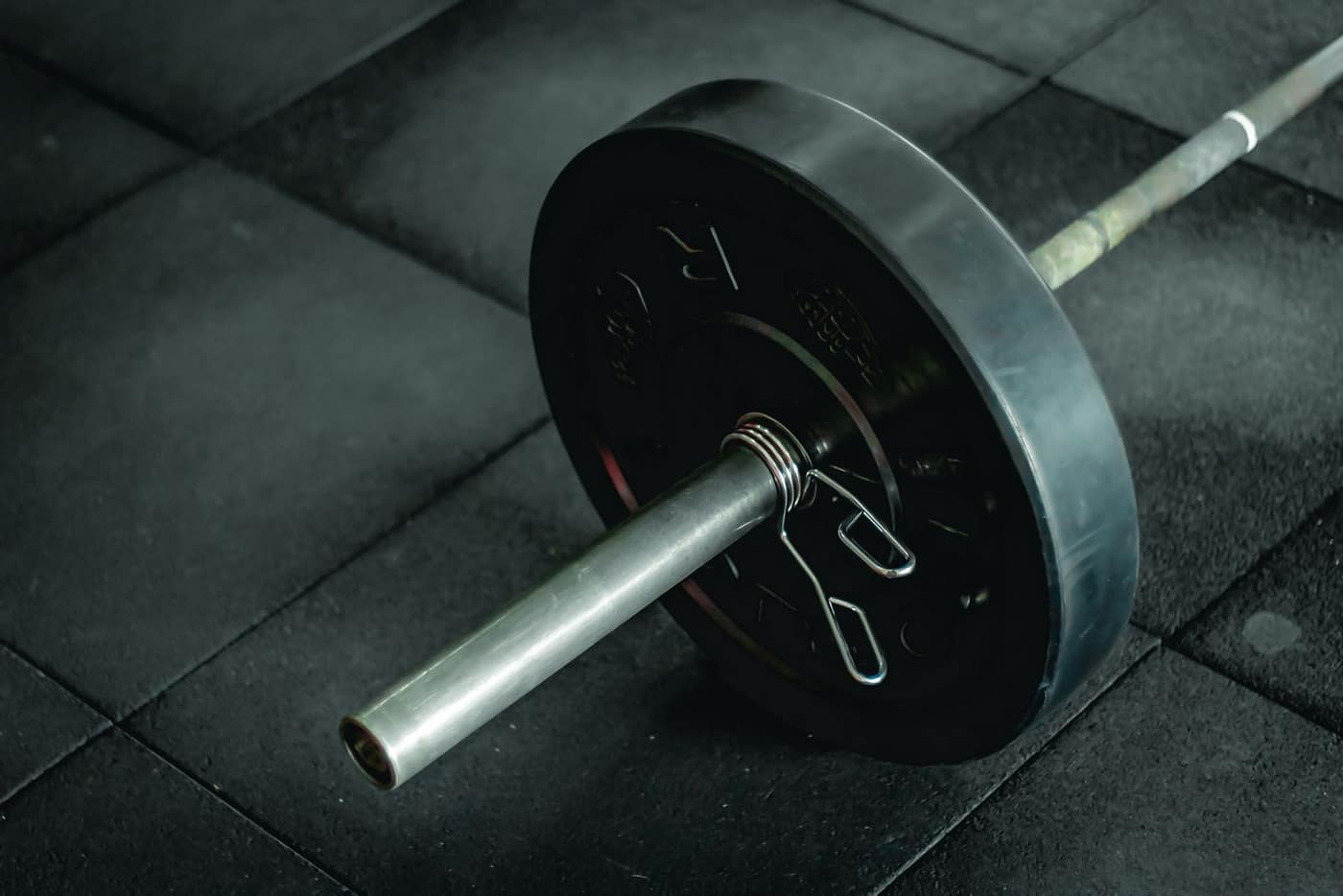 Loaded Olympic barbell with a rubber bumper plate resting on a gym floor