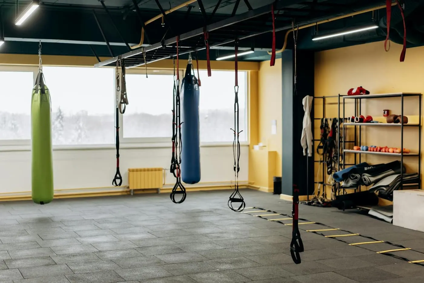 Functional training studio with heavy bags, suspension trainers, and an agility ladder