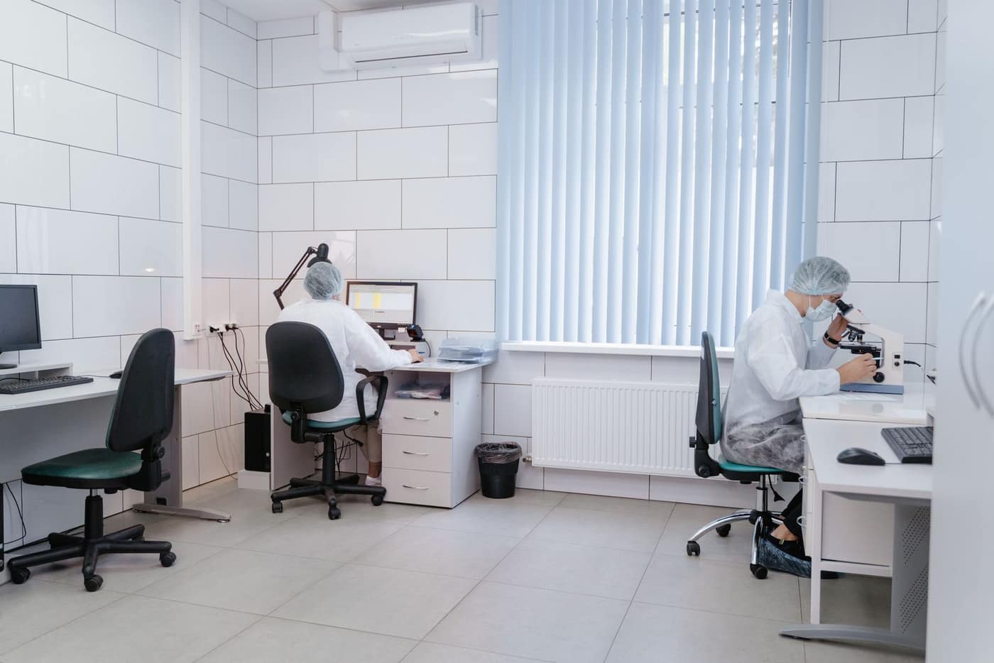 Lab technician handling reagents at a workstation above a seamless floor
