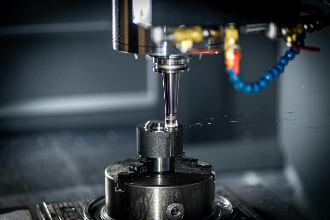 CNC machine cutting metal with coolant spray on a production floor