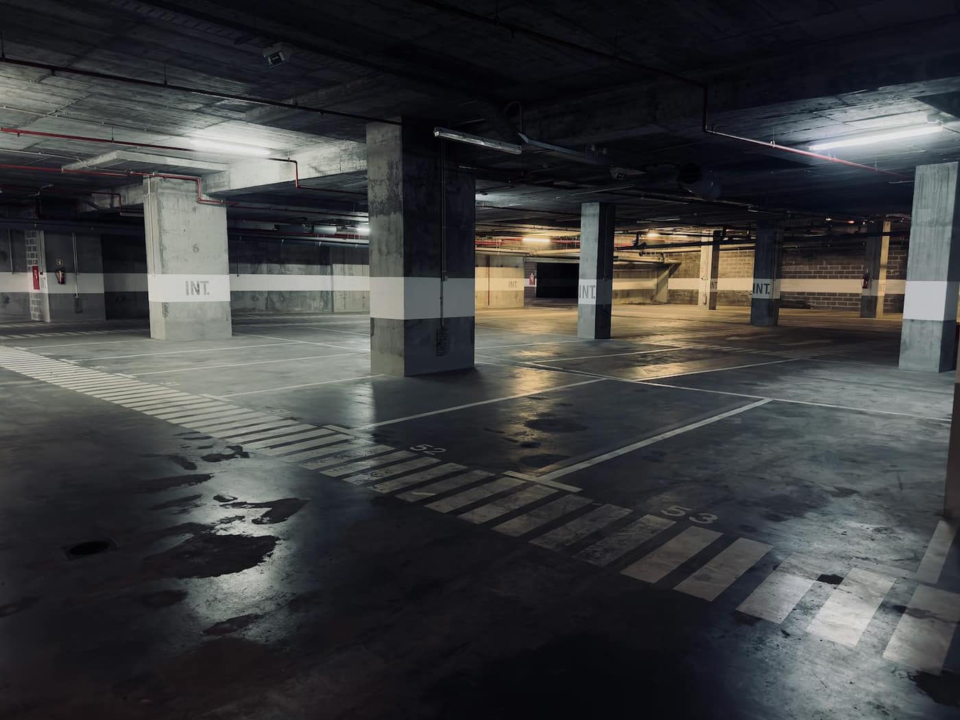 Empty parking-garage level with standing water pooled across the concrete deck
