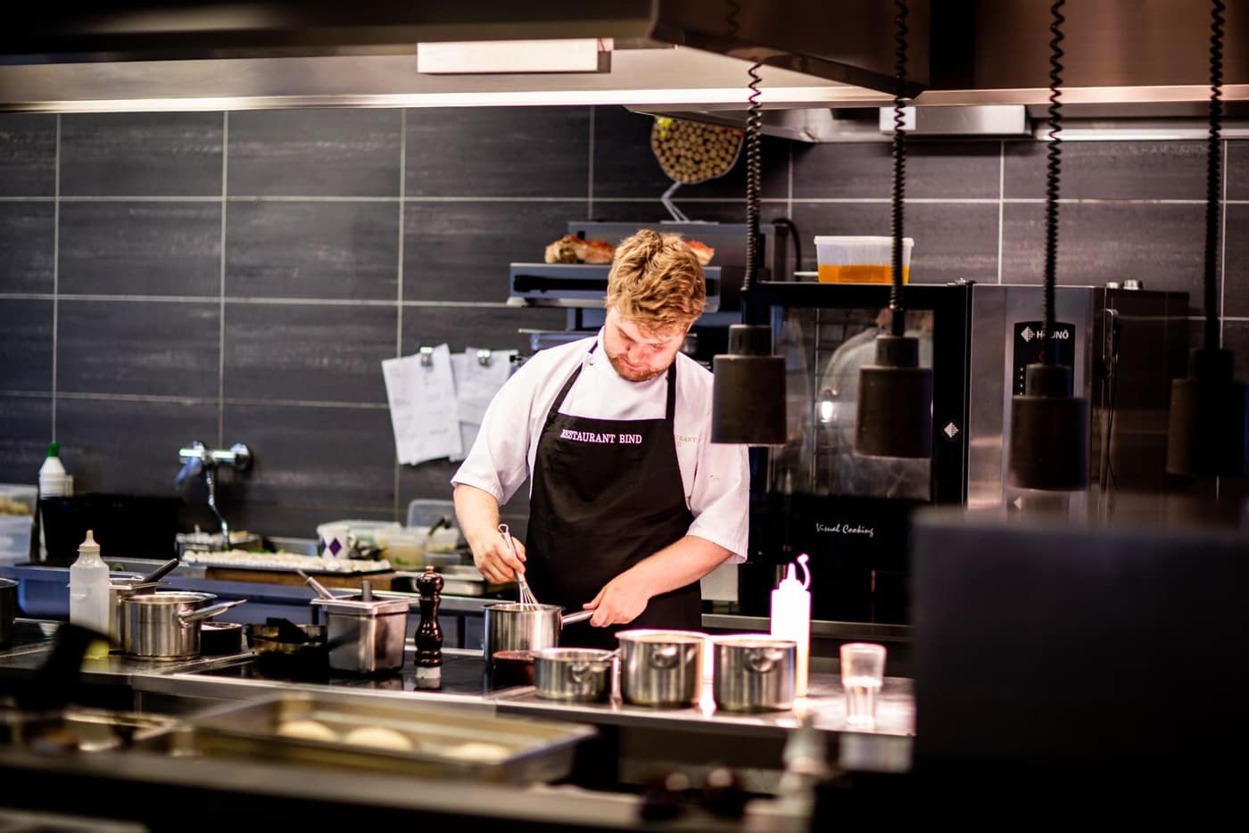 Chef working at a busy cookline above a hard-working kitchen floor
