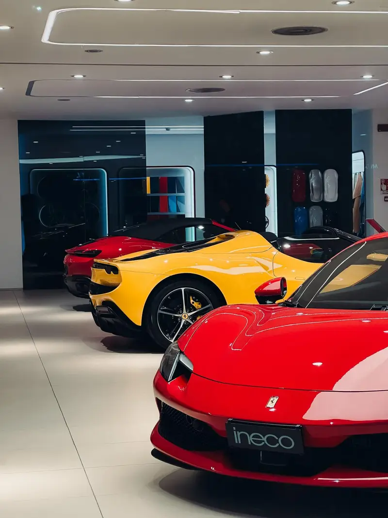 Luxury vehicles on display in a brightly lit showroom above a high-gloss reflective floor