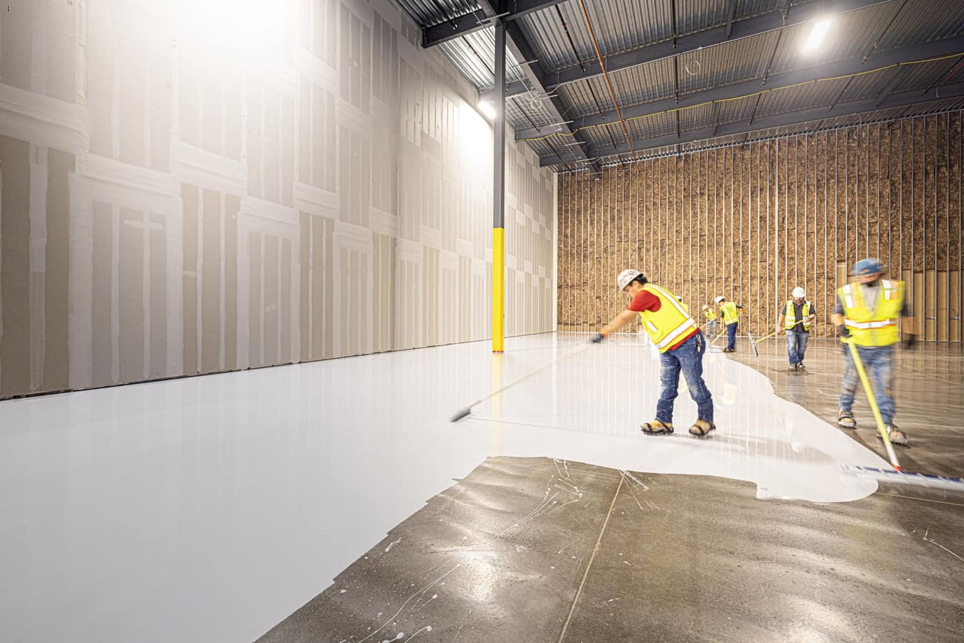 Crew placing and finishing a fresh industrial floor coating over a prepared slab