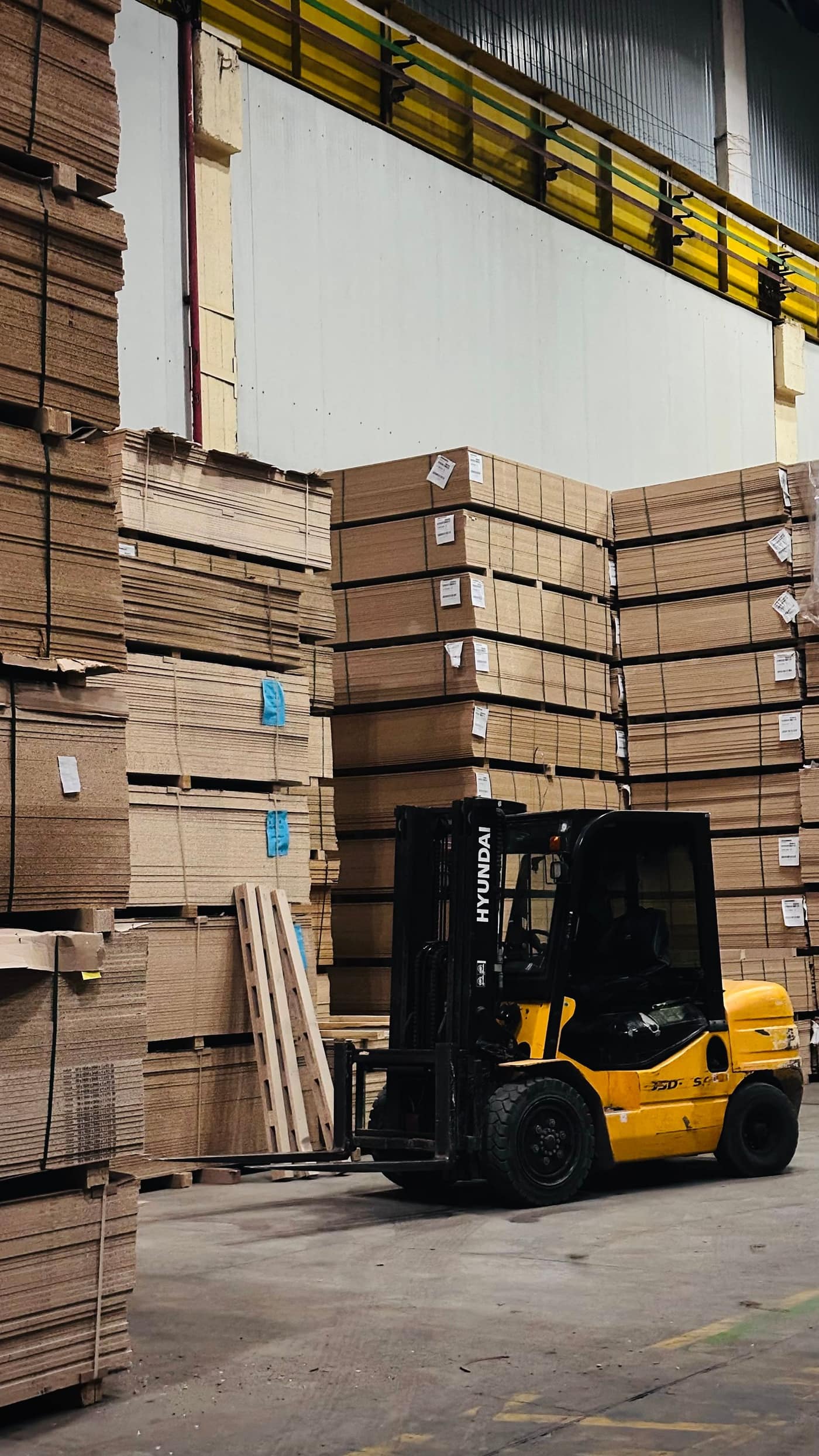 Forklift stacking loaded pallets in a busy distribution warehouse