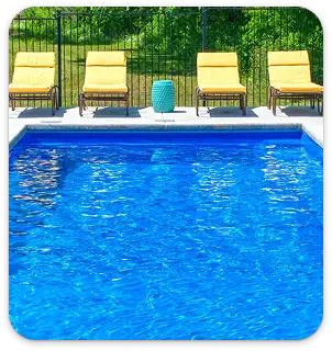 Vibrant blue epoxy pool deck finish with seating area and lush greenery background.